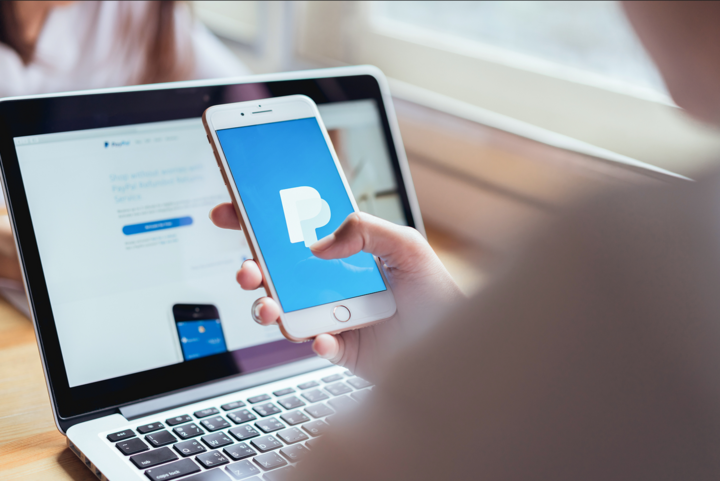 woman use smartphone on the table showing screen Paypal business account web pages. is a popular and international method of money transfer via the Internet.